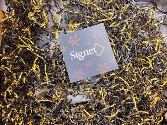 Black and gold crinkled paper strips and a card with Signet logo.