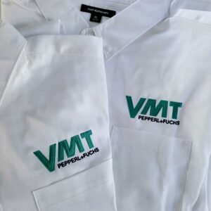 White folded button down shirts with the VMT logo embroidered on the left chest area.